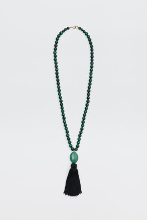Cally - Green is a necklace featuring small round green beads, a large oval green bead at the center, and a long black tassel hanging at the bottom, displayed on a white background.