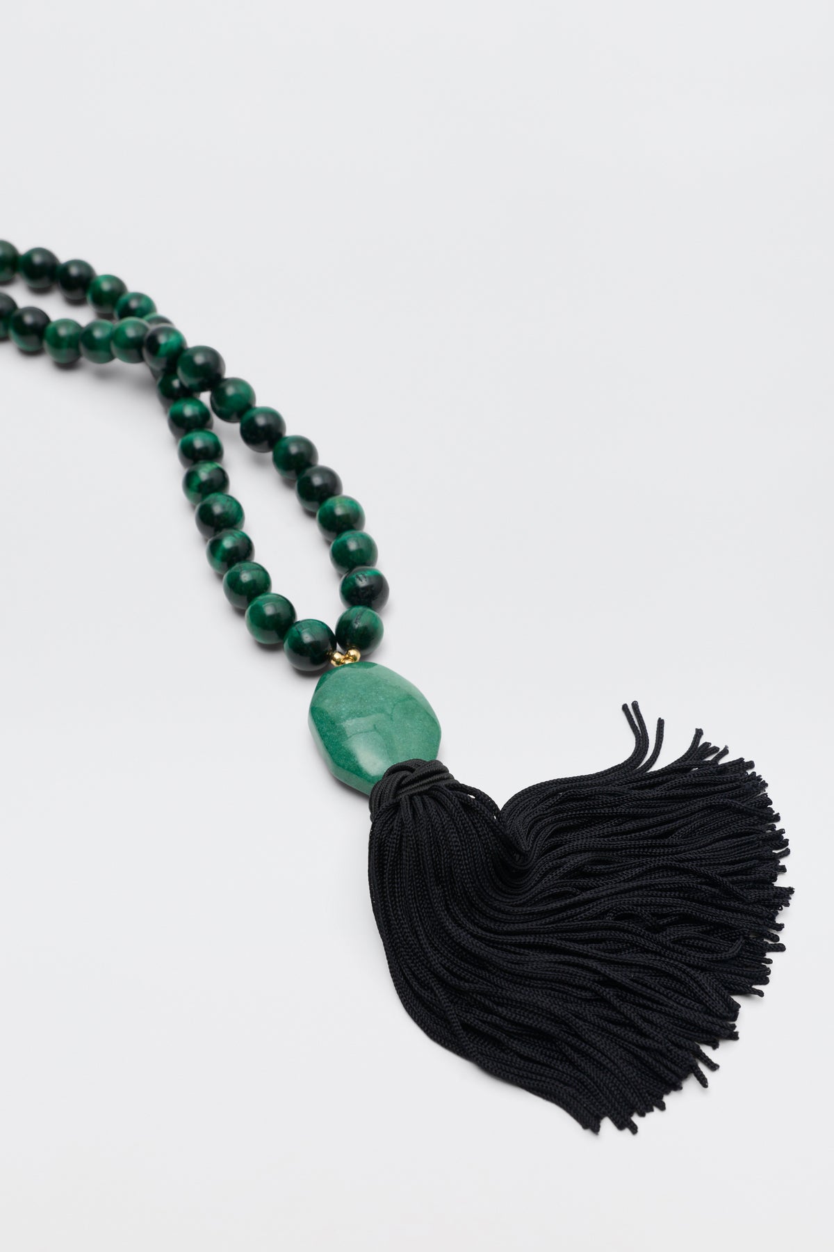 Cally - Green: A beaded green necklace featuring a large central green stone and a black tassel, displayed on a white background.