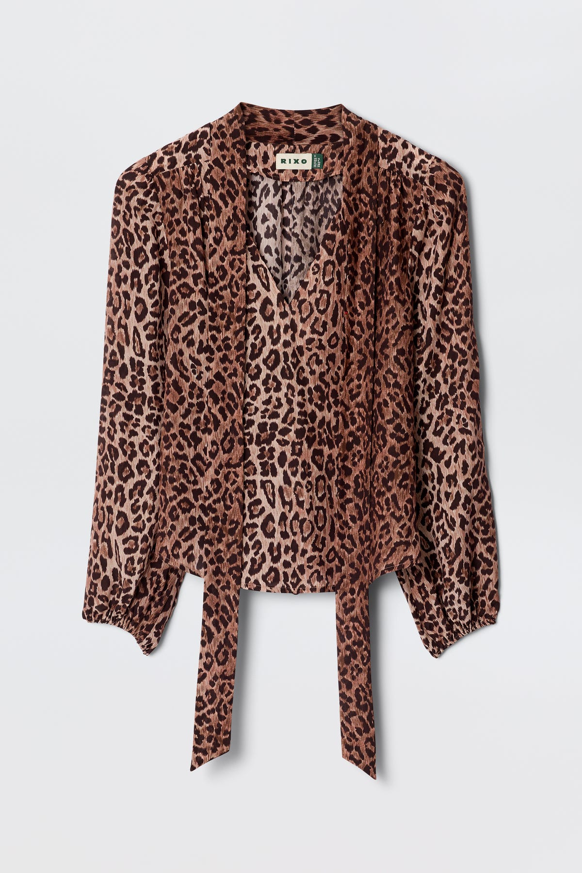 The Moss - Leopard Brown blouse features long sleeves, lightweight leopard-print silk, a V-neck, and front tie details, displayed on a plain light background for a vintage-inspired look.
