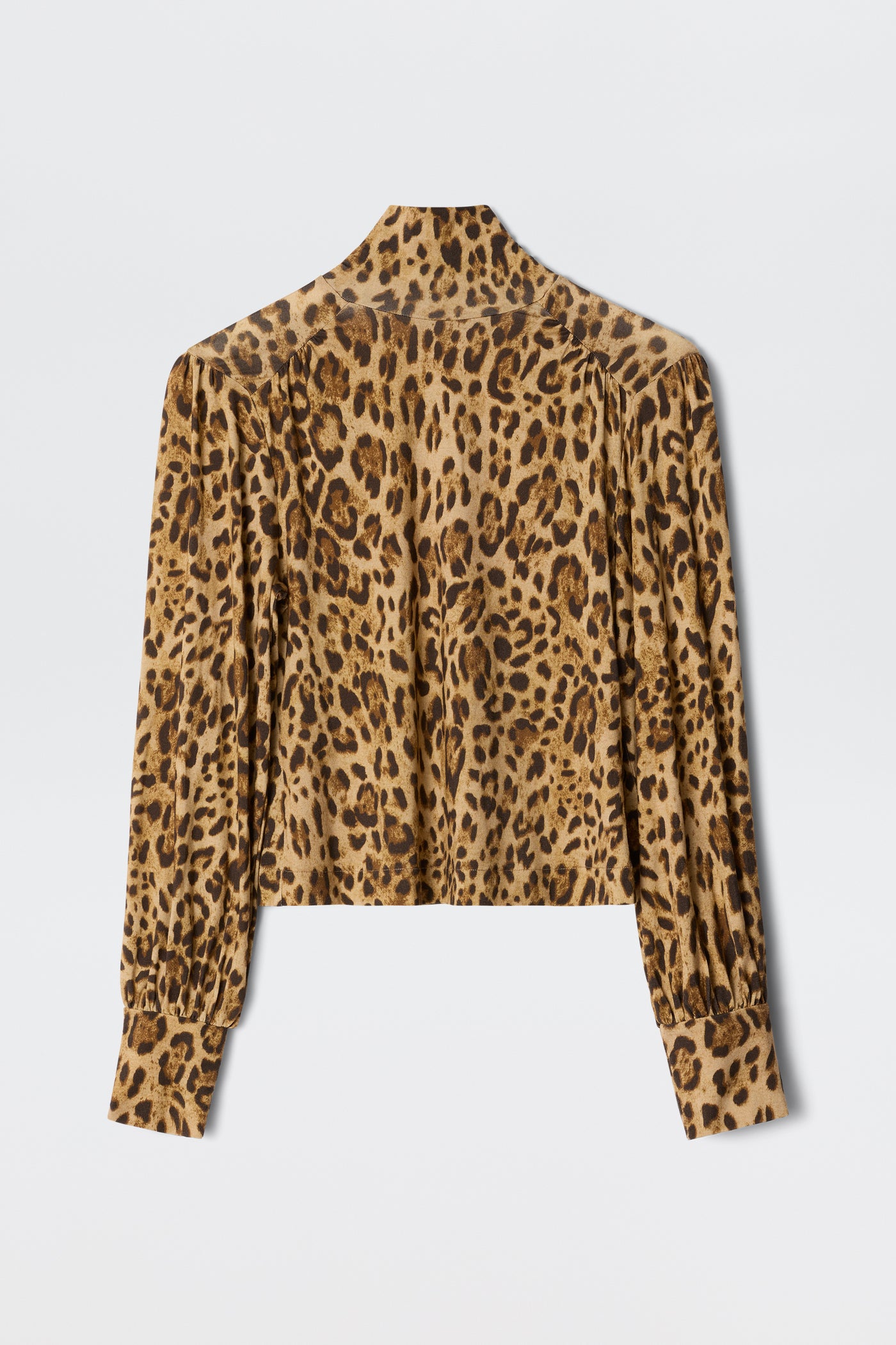 The Suki - Mila Leopard Brown is a long-sleeve, button-down blouse featuring a brown and black leopard print, shown flat with the back visible—ideal for layering over turtlenecks or jerseys for extra warmth and style.
