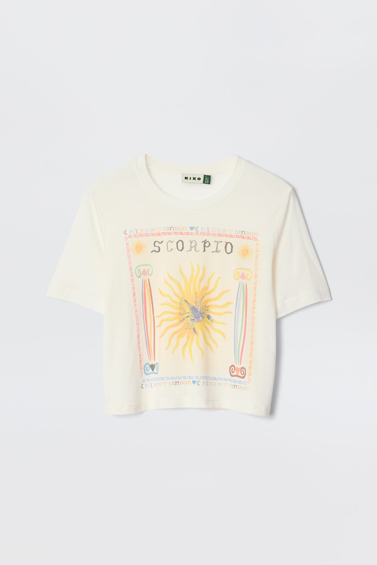 The Ria - Scorpio is a white cropped T-shirt with a vibrant Scorpio illustration—sun, scorpion, and zodiac symbols—designed to pair perfectly with RIXO skirts. Laid flat on a plain background for an eye-catching astrological statement.