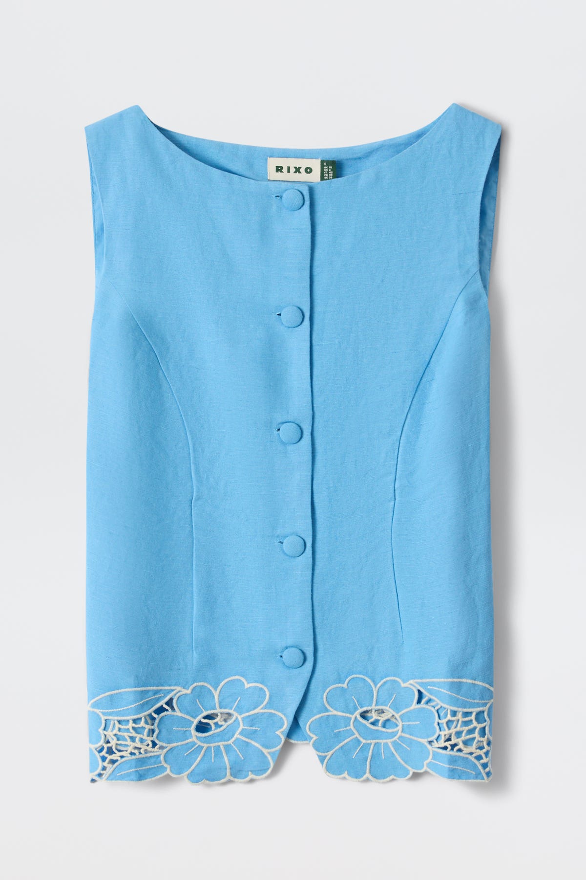 The Lucca - Daisy Cutwork Embroidery Blue is a sleeveless duck egg blue linen top with a boat neckline, button-up front, and large floral cutwork embroidery along the hem, crafted from lightweight fabric for an elegant fitted look.
