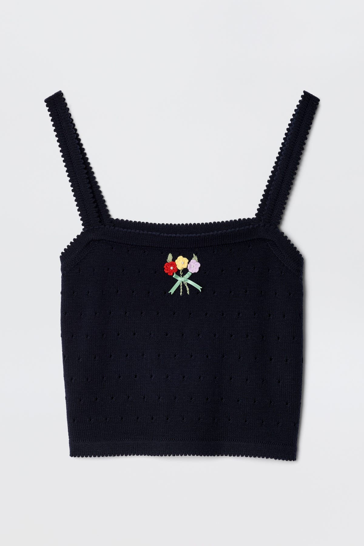 The Perla - Floret Embroidery Deep Navy is a black merino wool crop top with spaghetti straps, featuring a small embroidered bouquet of red, yellow, and pink flowers with green stems at the front center.