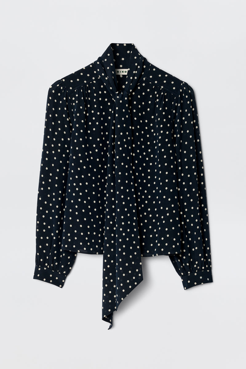 The Melaina - Layla Dot Navy is a stylish navy shirt with a chic scarf neckline, perfect for elevating any look.