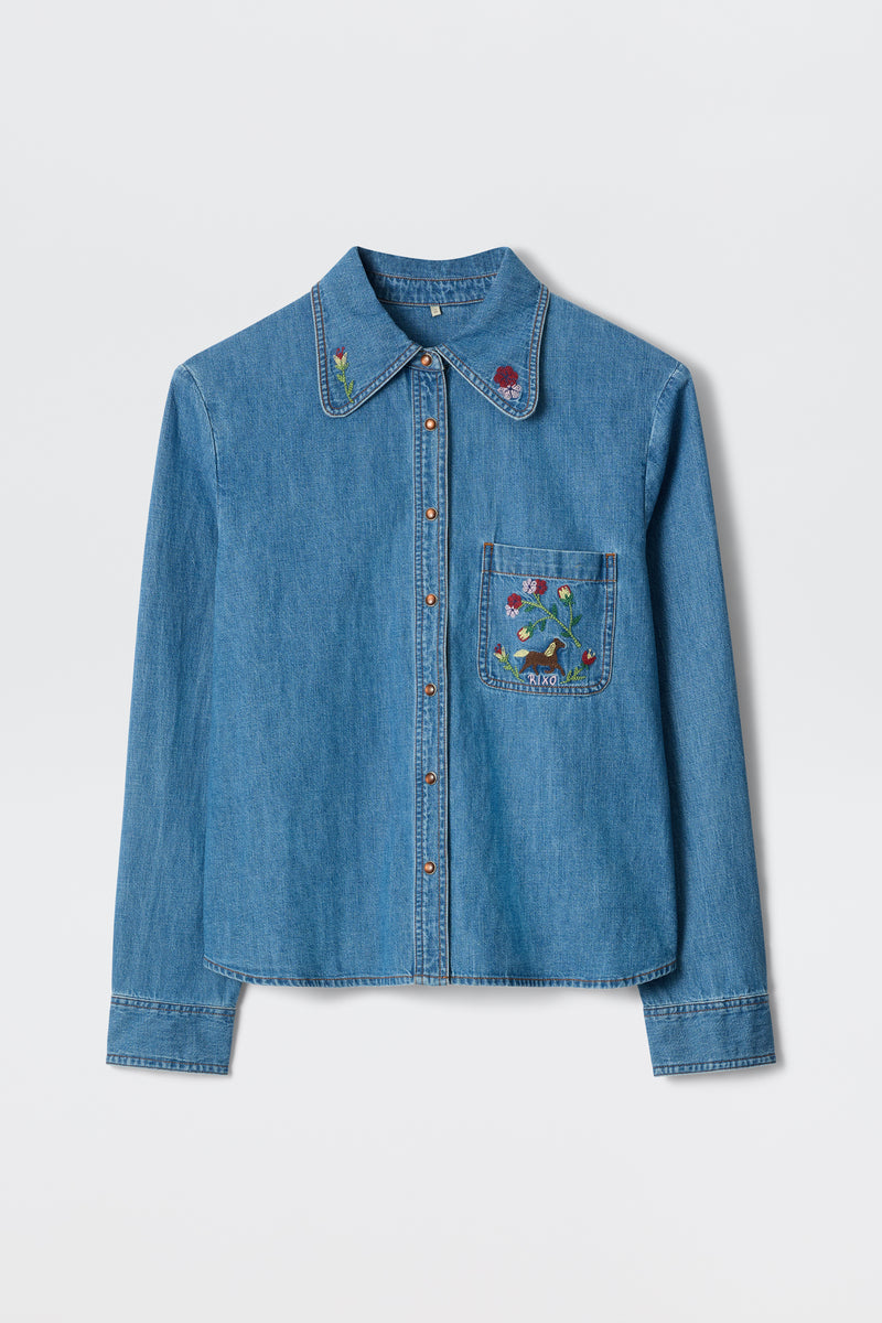 The Edaline Sadie Embroidery Light Vintage is a long-sleeved blue denim shirt with red buttons, floral embroidery on the left chest pocket, and small flower details on the collar, shown against a white background.