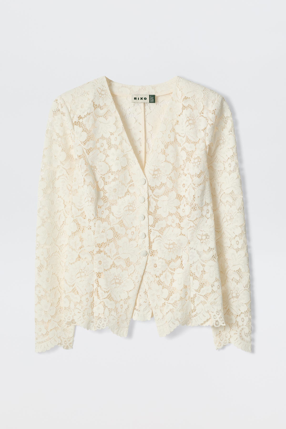 The Padma - Cream is an off-white, long-sleeved lace cardigan with a V-neckline and delicate floral pattern, shown flat on a light background.
