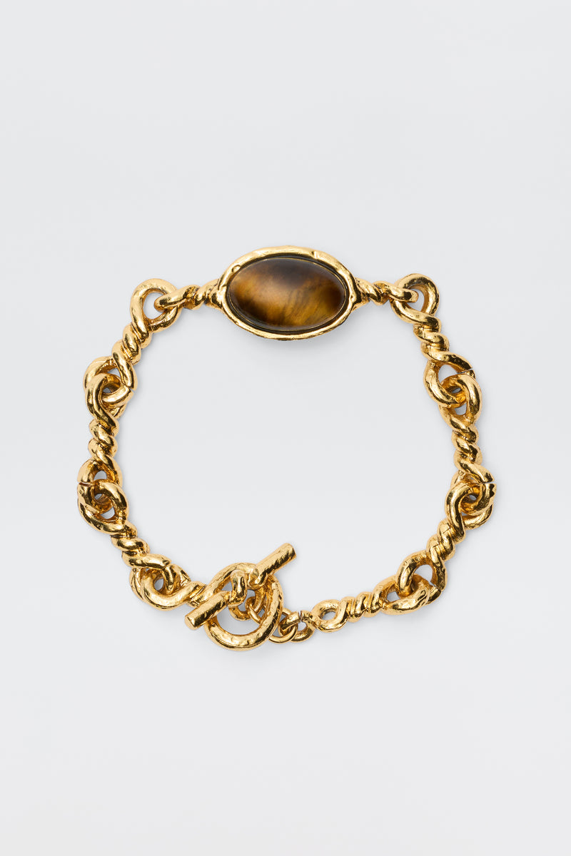 The Maelis - Gold is a vintage-inspired bracelet with chunky gold-plated twisted links and a central oval brown gemstone, displayed on a plain white background.