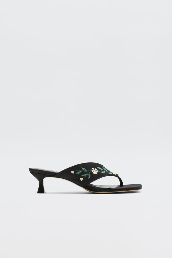 The Zoya - Blossom Embroidery Black sandals are black open-toe satin heels with a low kitten heel and yellow-green floral embroidery on the strap, shown against a plain white background.
