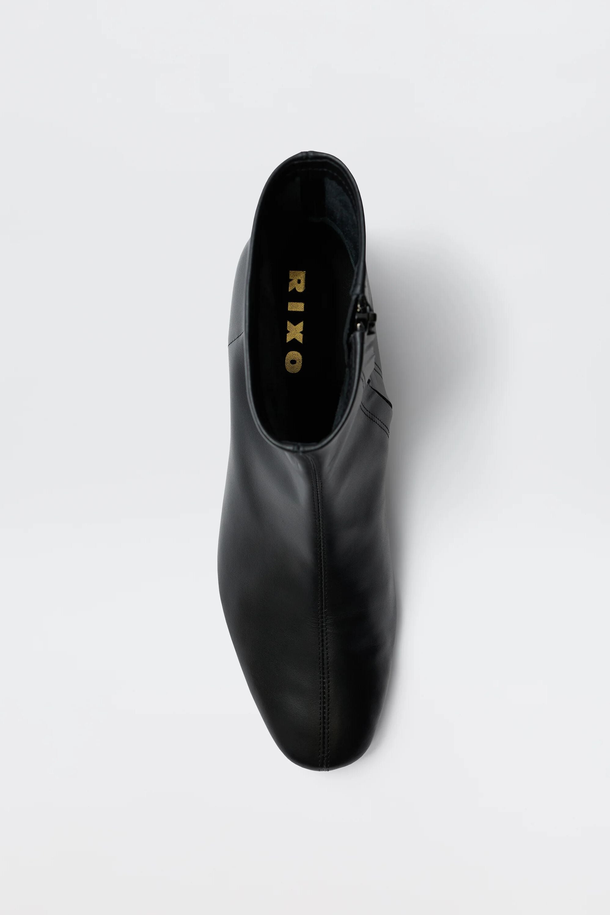 Top view of the Rey - Black Leather ankle boot, featuring a rounded toe and visible gold RIXO branding on the insole, set against a plain white background.