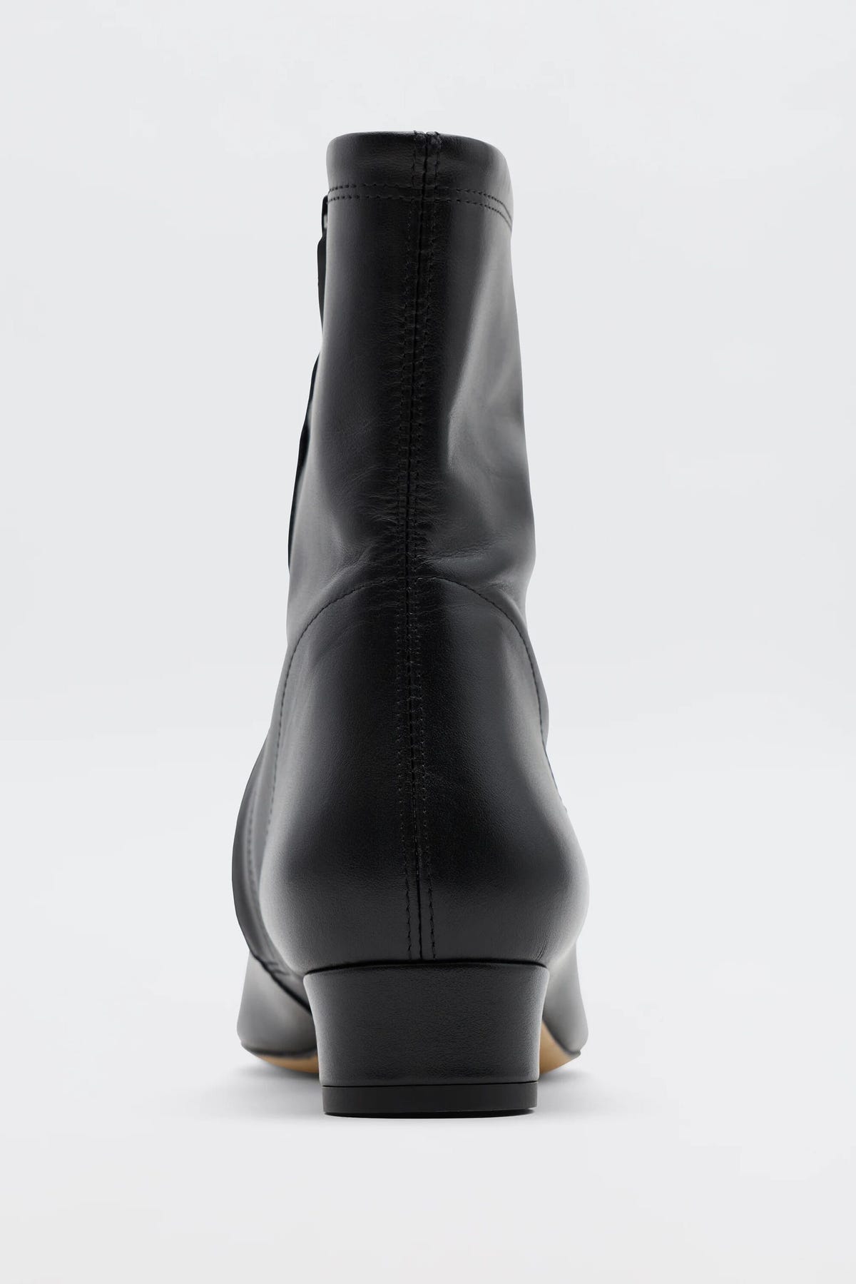 The Rey - Black Leather ankle boot is shown from the back on a plain white background, highlighting its heel, seam details, and smooth finish for a vintage-inspired look.
