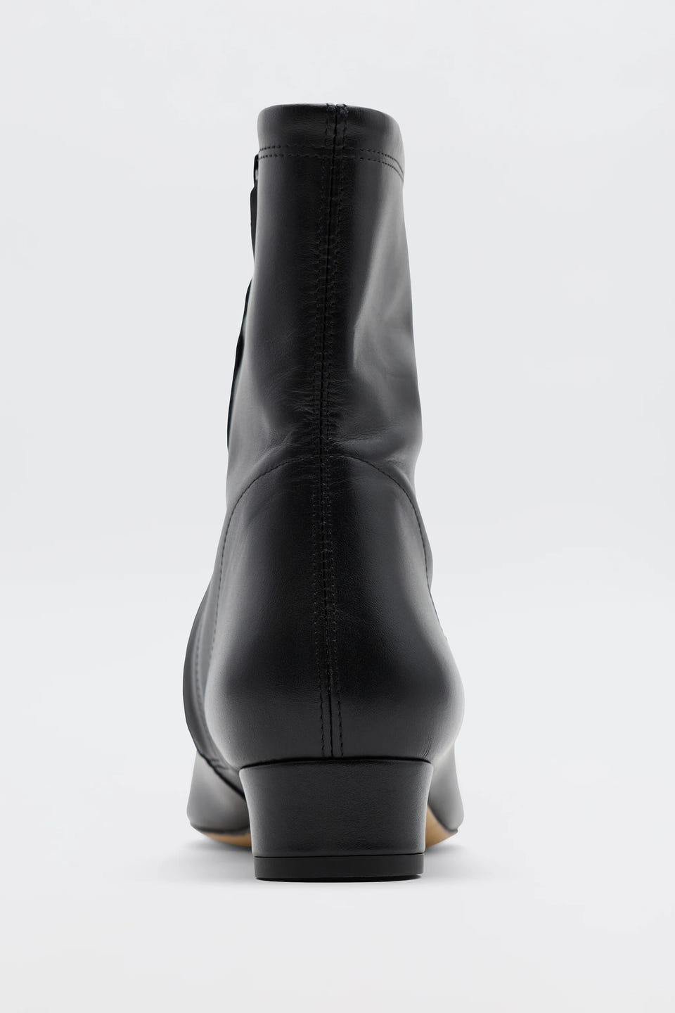 The Rey - Black Leather ankle boot is shown from the back on a plain white background, highlighting its heel, seam details, and smooth finish for a vintage-inspired look.