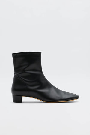 The Rey - Black Leather ankle boot features a low heel, pointed toe, and minimalist design for vintage-inspired elegance. Its sleek side profile stands out in smooth black leather against a plain white background.