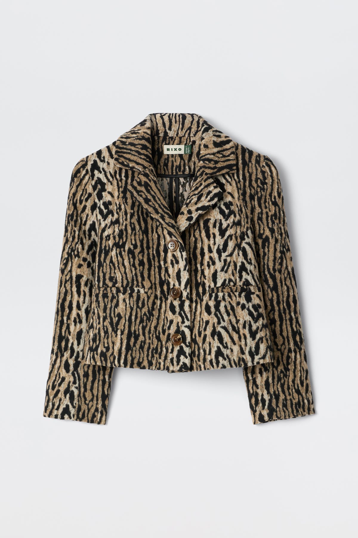 The Leila - Bohemia Leopard Brown is an elegant cropped button-up jacket with a bold beige, brown, and black leopard print, collar, and front pockets. Inspired by vintage souvenir jackets, it's shown on a plain white background.