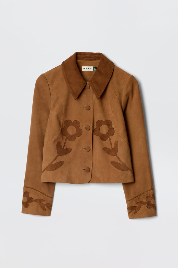 The Dionne - Retro Daisy is a brown suede jacket featuring a wide collar, button-up front, and decorative dark brown floral patterns on the front and cuffs, inspired by classic vintage souvenir jacket styles.