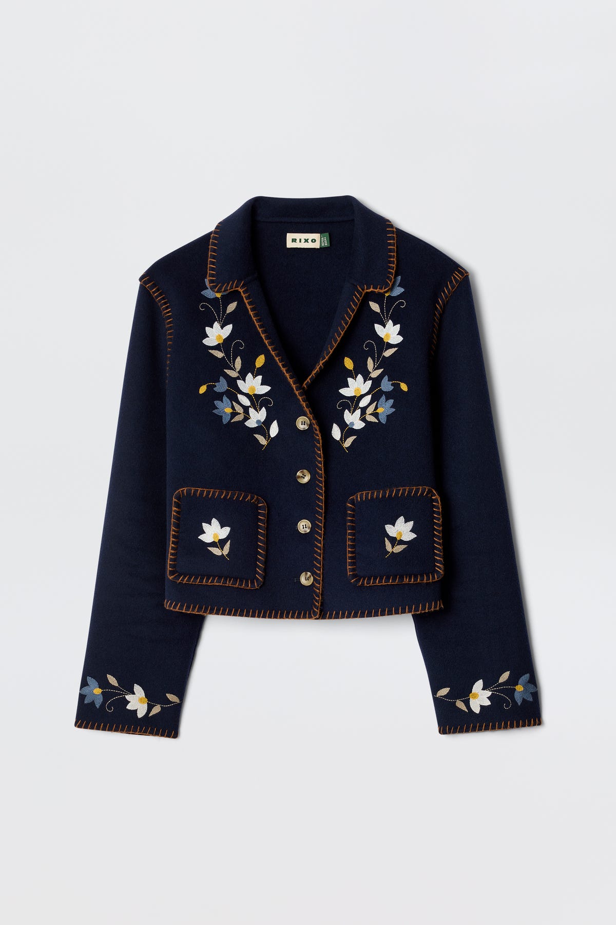The Sunday - Petal Embroidery Navy is a luxurious cropped jacket in navy wool blend, featuring floral embroidery on the front and lapels, brown decorative edge stitching, and silver buttons.