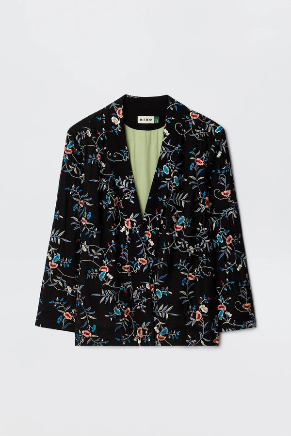 The Malachy - Botanical Embroidery Black is a black blazer with red, blue, and white embroidered botanical motifs, a light green lining, made from lightweight crepe. Shown on a plain white background.