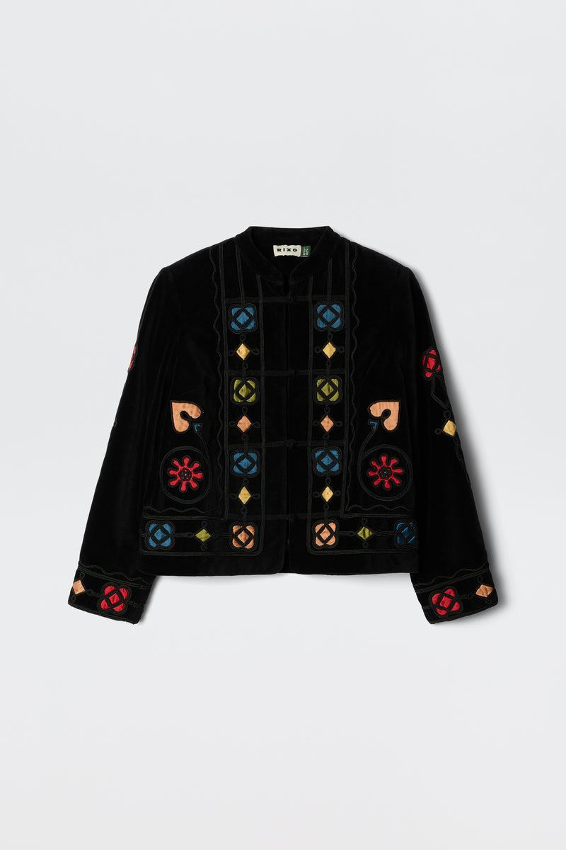 The Viktoria - Serino Applique Black jacket features black velvet and colorful embroidered geometric and floral patterns in red, blue, yellow, and beige, displayed on a plain white background.