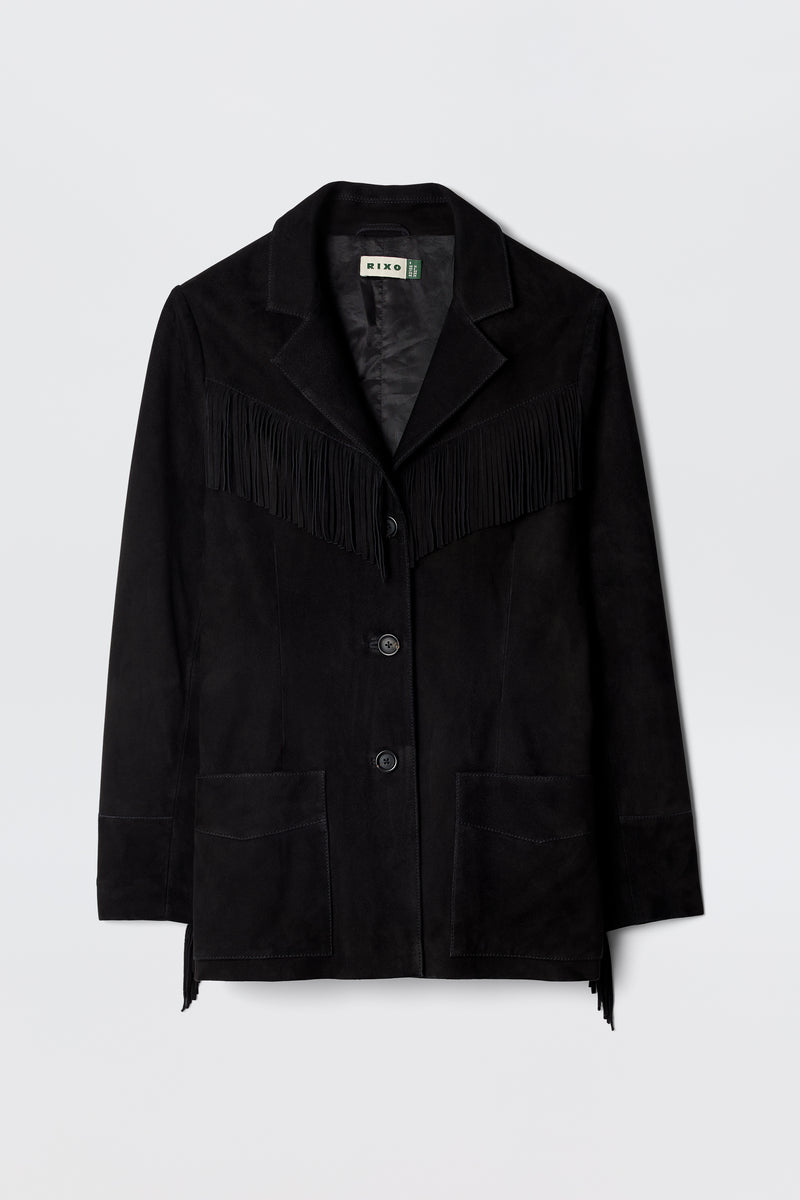 The Teagan - Black is a suede blazer-style jacket with fringe across the chest and back, front button closure, notched lapels, and two large pockets, shown on a plain light background.
