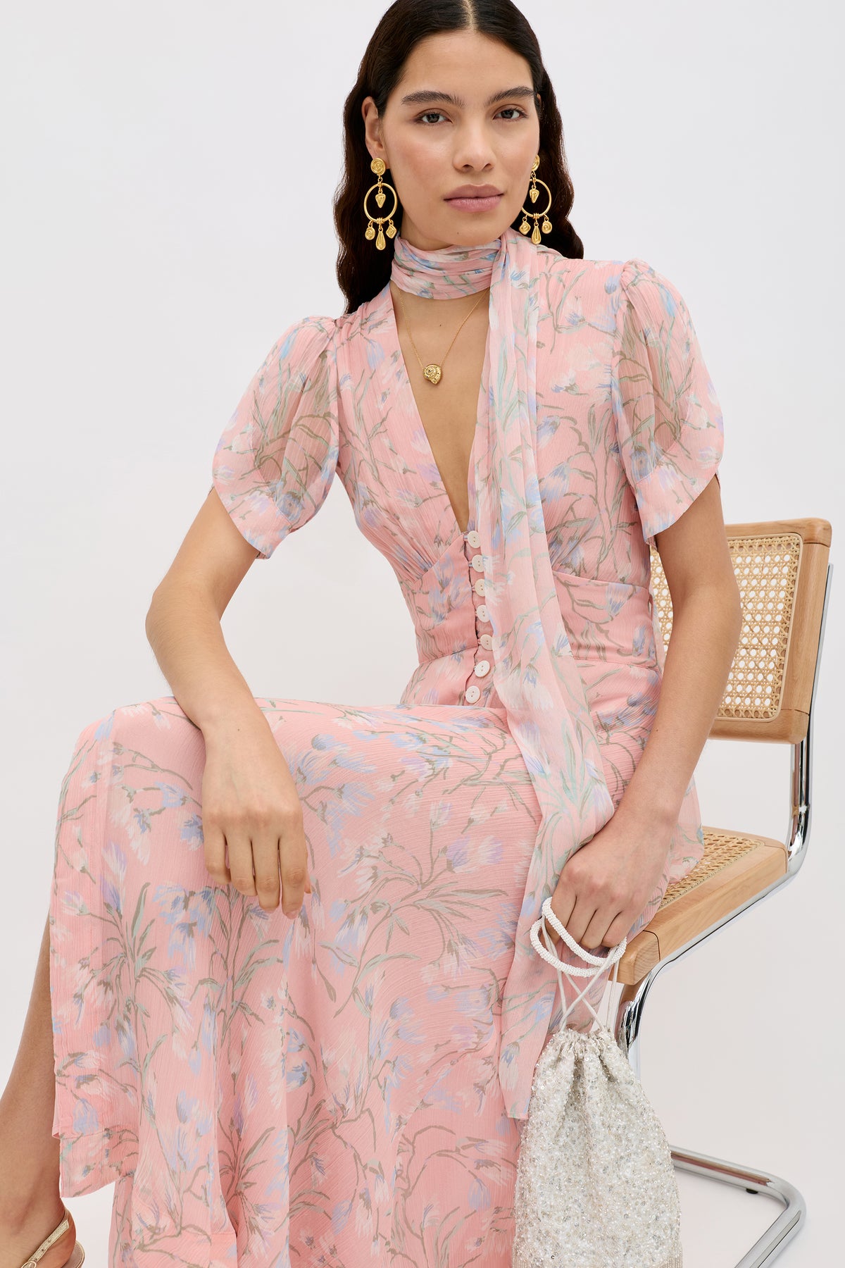 A woman sits on a chair adorned with the Julien - Watercolour Floral Pink fabric.