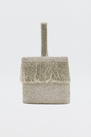 The Zenni - Beaded Silver clutch, a small box-shaped silver bag with a beaded texture, fringe on the top edge, and a single rounded handle, is shown as an elegant occasion accessory against a plain white background.