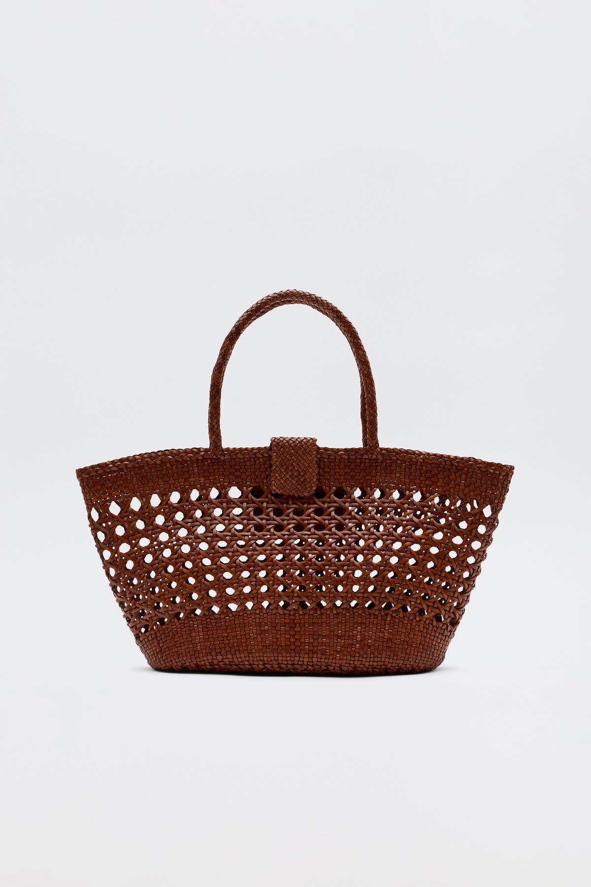 The Lucine - Tan is a brown woven straw tote bag with an openwork pattern, two handles, and a small flap closure, shown against a plain white background.