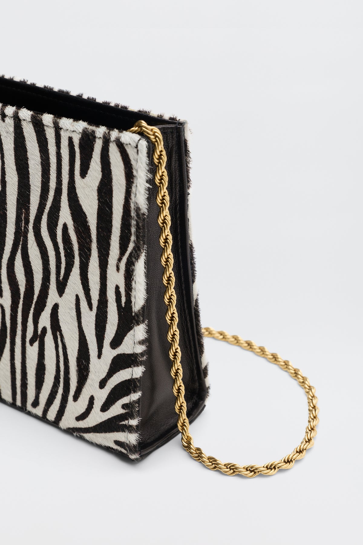 Kamila - Zebra Print Brown handbag with a brown and white zebra print pattern and a thin gold chain strap.