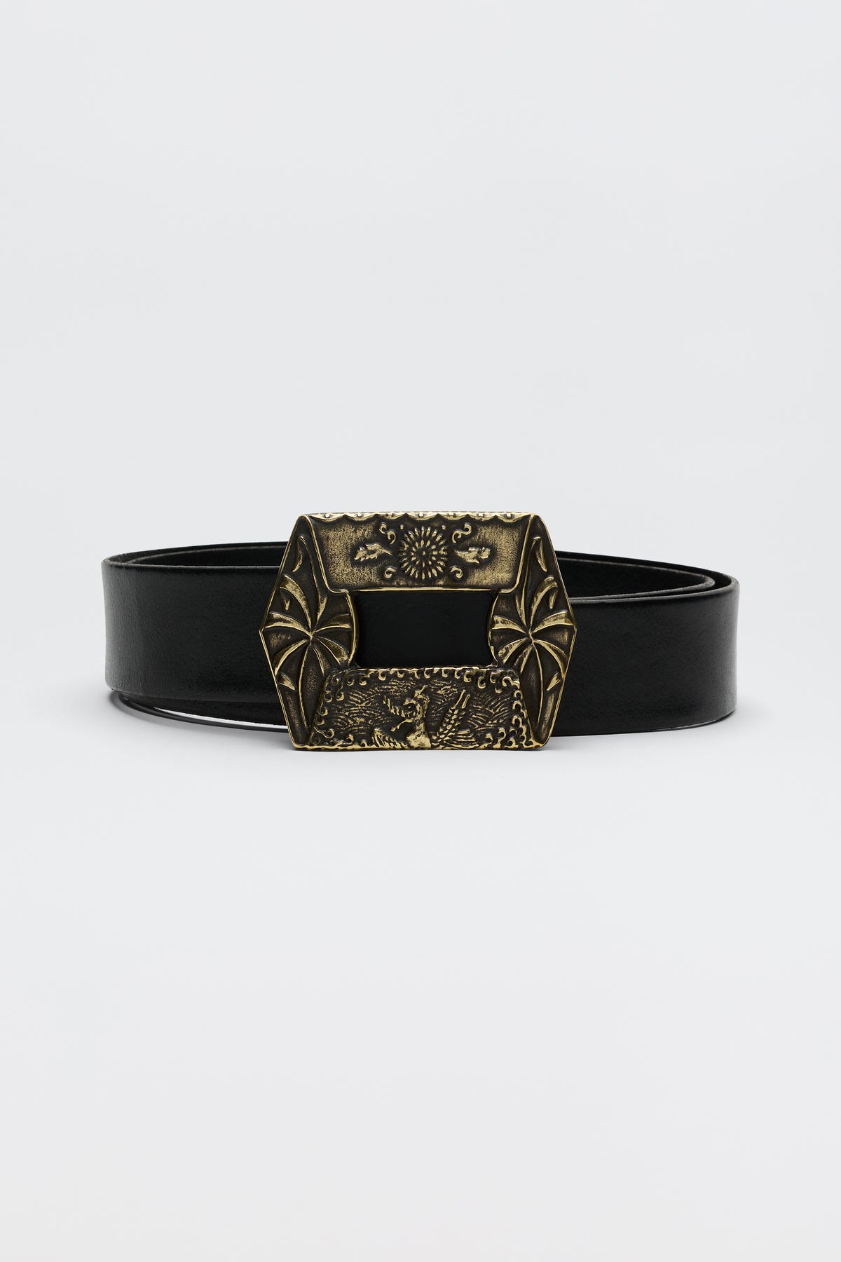 The Rhianna - Black is a black leather belt with a large, ornate brass buckle adorned with decorative engravings and geometric patterns, showcased against a plain white background.