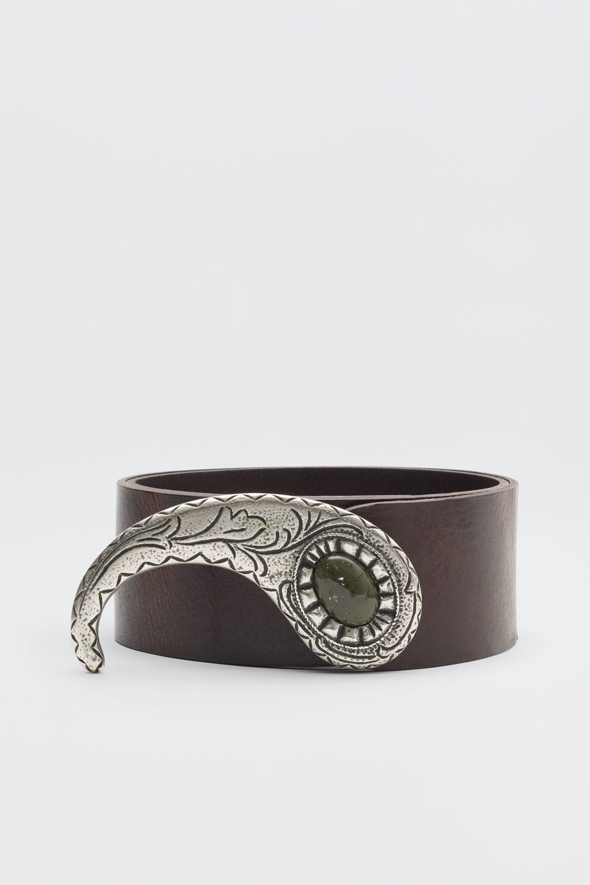 The Daniella - Dark Brown is a leather belt with a large, ornate silver buckle featuring engraved details and a central dark green stone, shown against a plain white background.