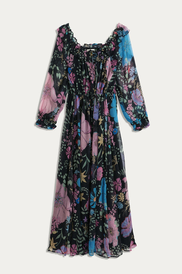 The Alina – Bhatia Floral Black dress is a bohemian, ankle-length design with long sleeves, ruffled neckline and cuffs, featuring vibrant pink, blue, and purple florals on black. Its flowy gathered waist and sheer fabric offer effortless charm.