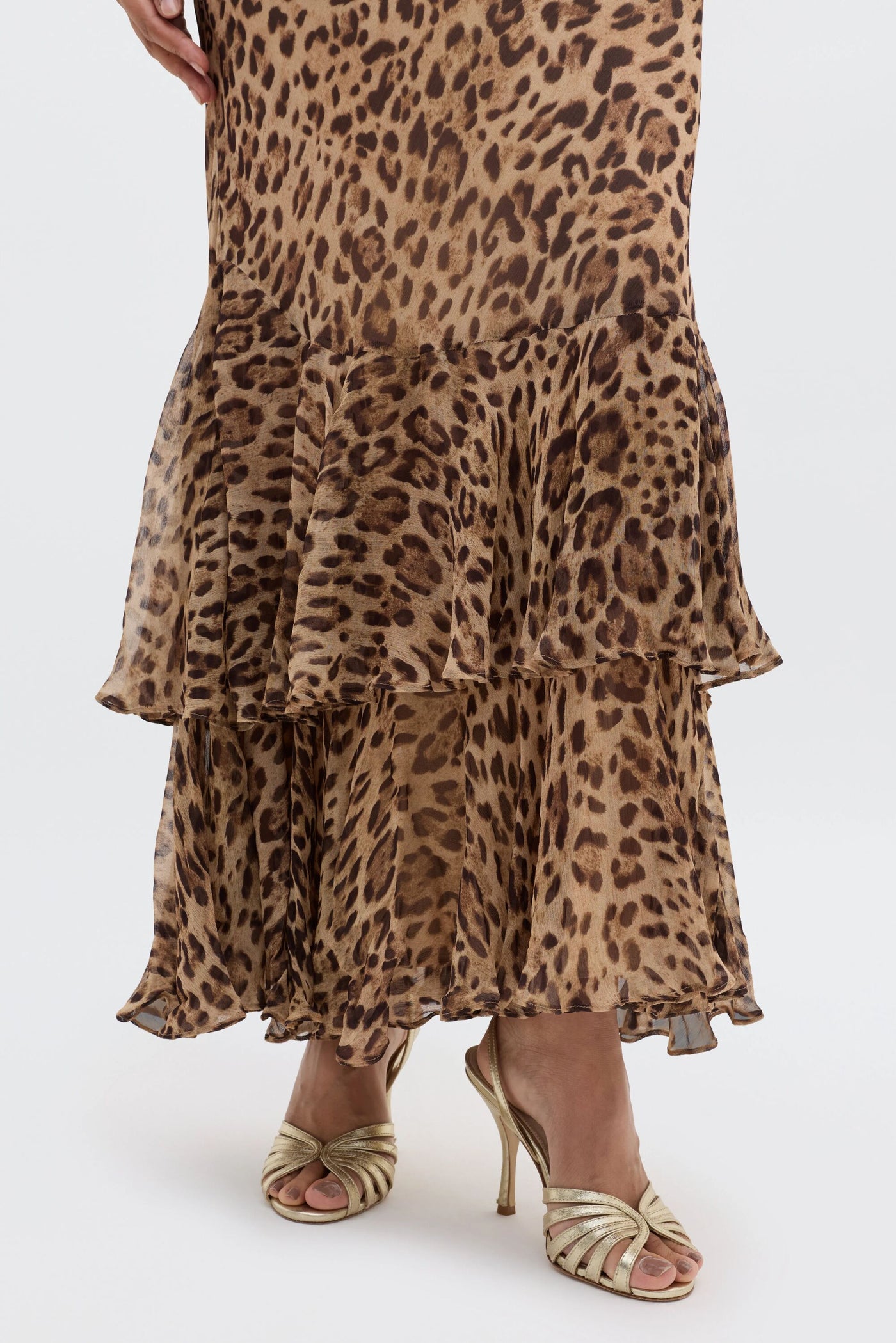 A person wearing the Ordinia - Mila Leopard Brown skirt with gold high heels stands against a white background—a chic choice for black-tie weddings.