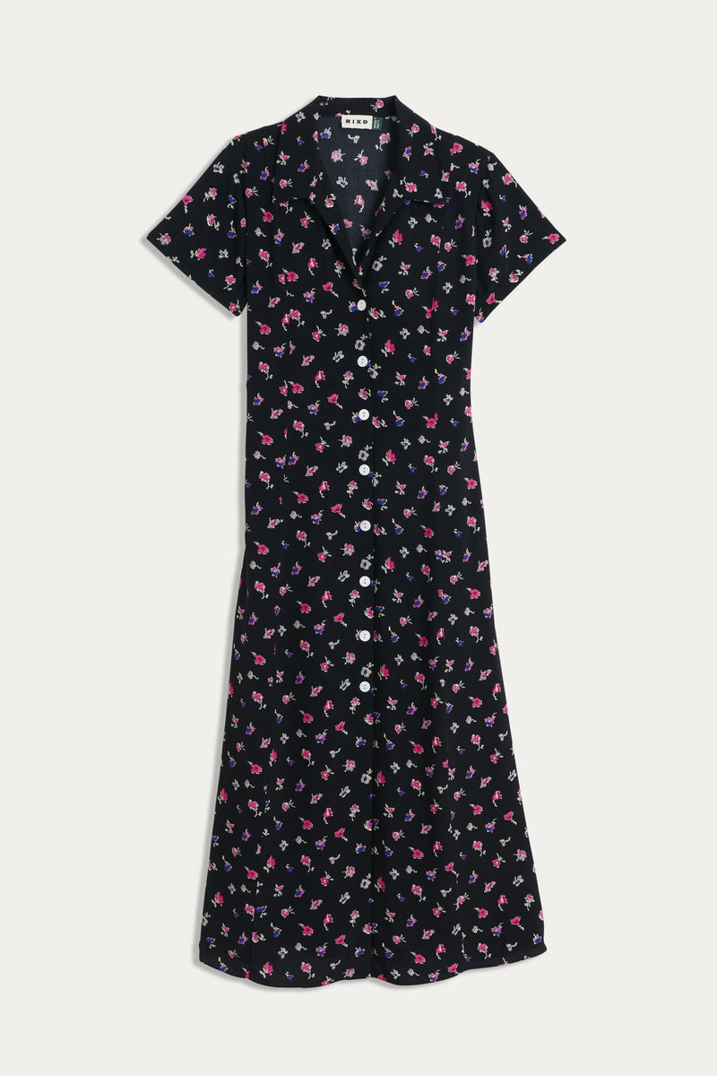 The Florrie - French Ditsy Black is a vintage-inspired, black midi tea dress with short sleeves, a collar, button-down front, and a pink and purple floral ditsy print.