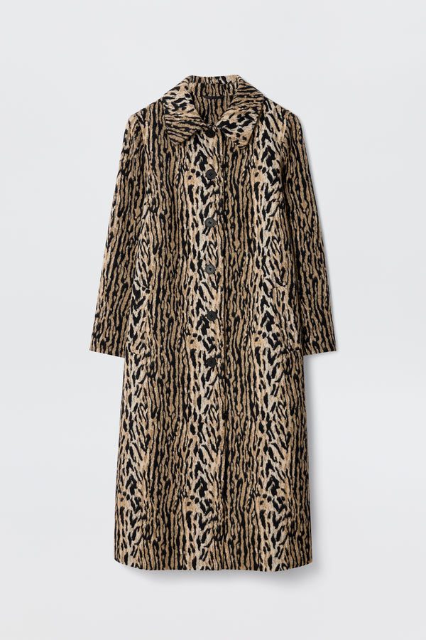 The Milly - Bohemia Leopard is a mid-length coat in tan and black with a bold leopard print, wide collar, and long felt fur sleeves, shown against a plain white background.