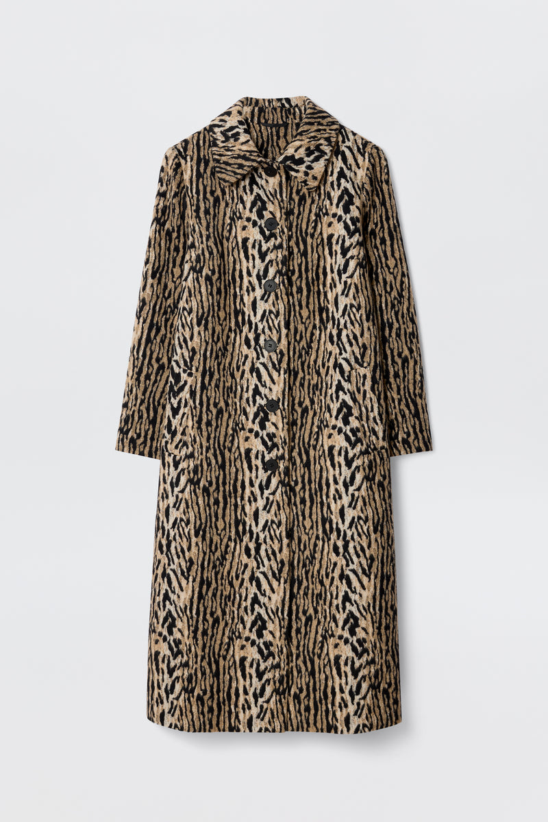 The Milly - Bohemia Leopard is a mid-length coat in tan and black with a bold leopard print, wide collar, and long felt fur sleeves, shown against a plain white background.