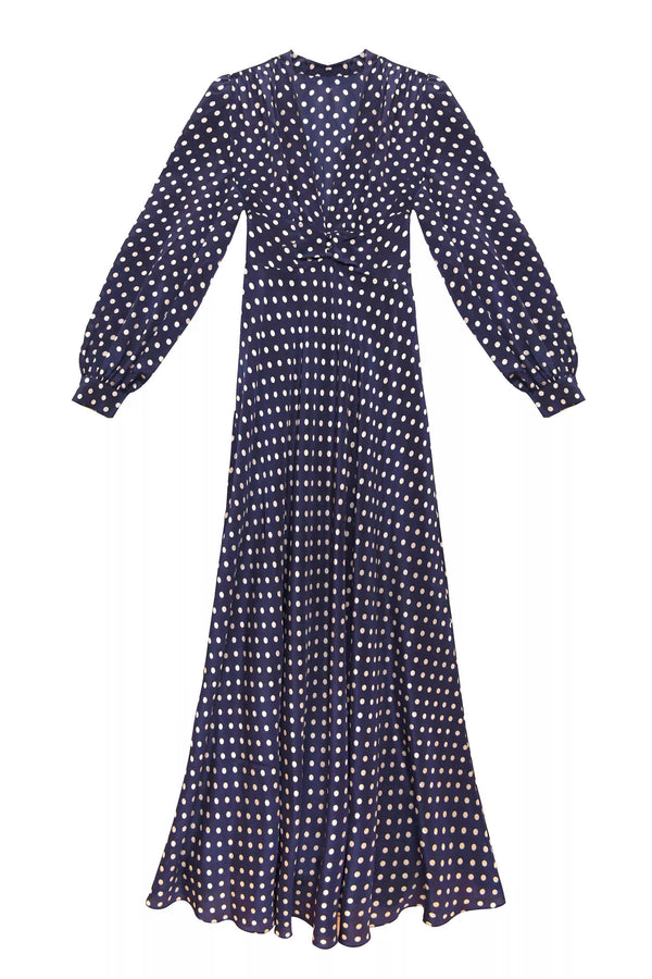 The Emory - Runway Spot Navy is a long-sleeved, floor-length dress with a fitted waist, featuring classic white polka dots on a navy background.