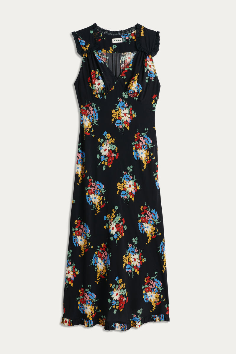 The Chessie - Darcie Floral Black is a sleeveless black midi dress featuring a colorful floral print, v-neckline, and ruffled details on the shoulders and hem, shown laid flat on a white background.