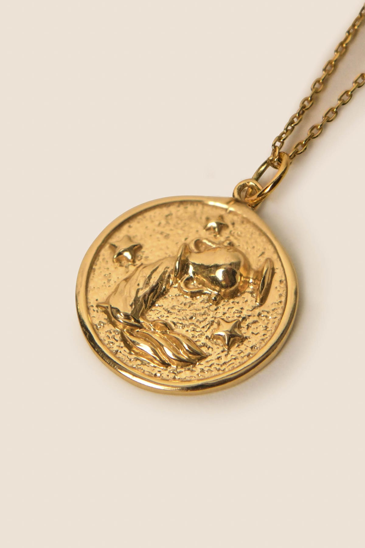 A gold vermeil pendant necklace featuring an embossed Aquarius design of stars and a planet, hanging from a simple gold chain on a light background—perfect for those who love celestial jewelry or zodiac necklaces.