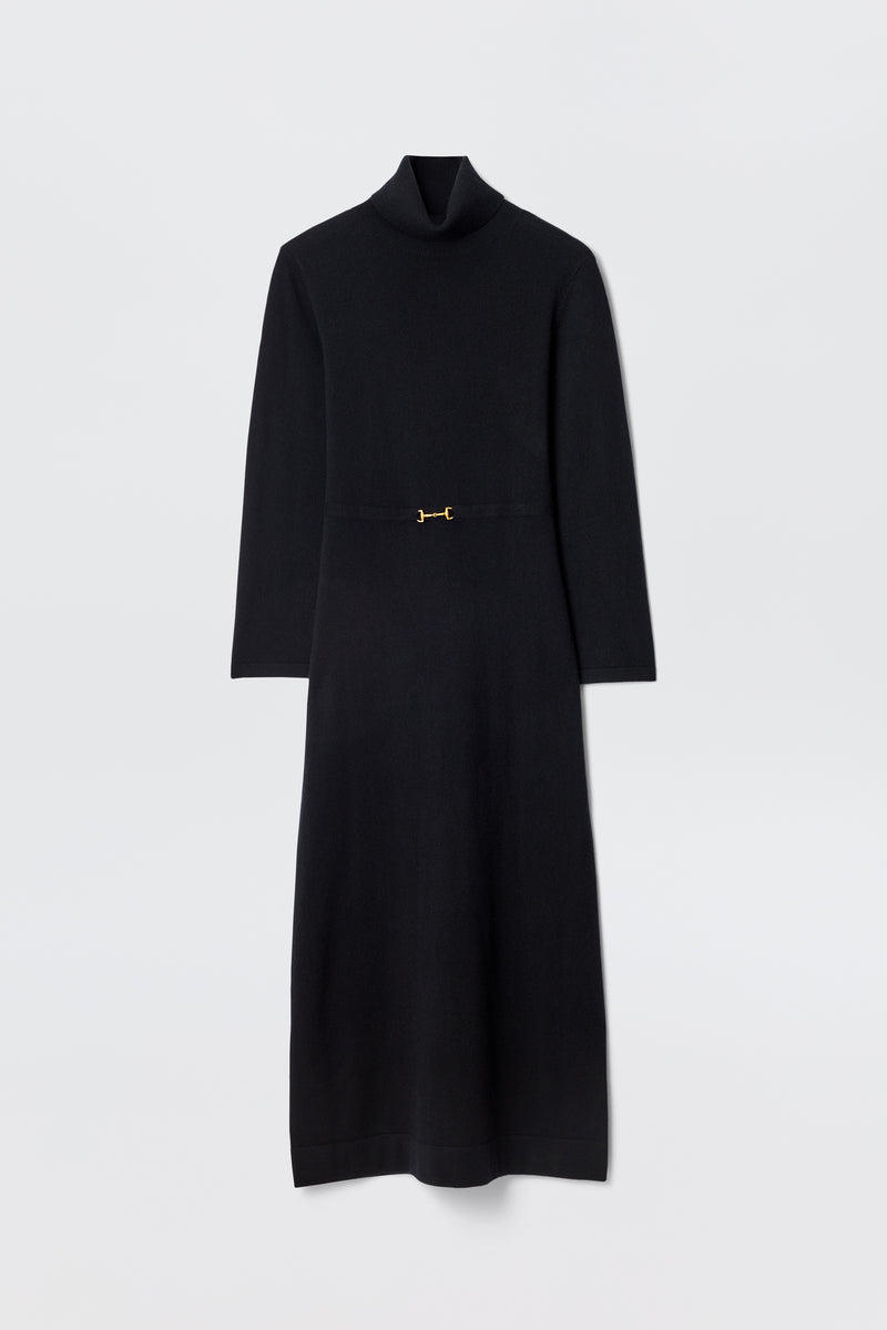 The Elliette - Black is a long-sleeved, minimalist black midi dress with a turtleneck, fitted waist, and a small gold clasp at the center, shown flat against a plain white background.