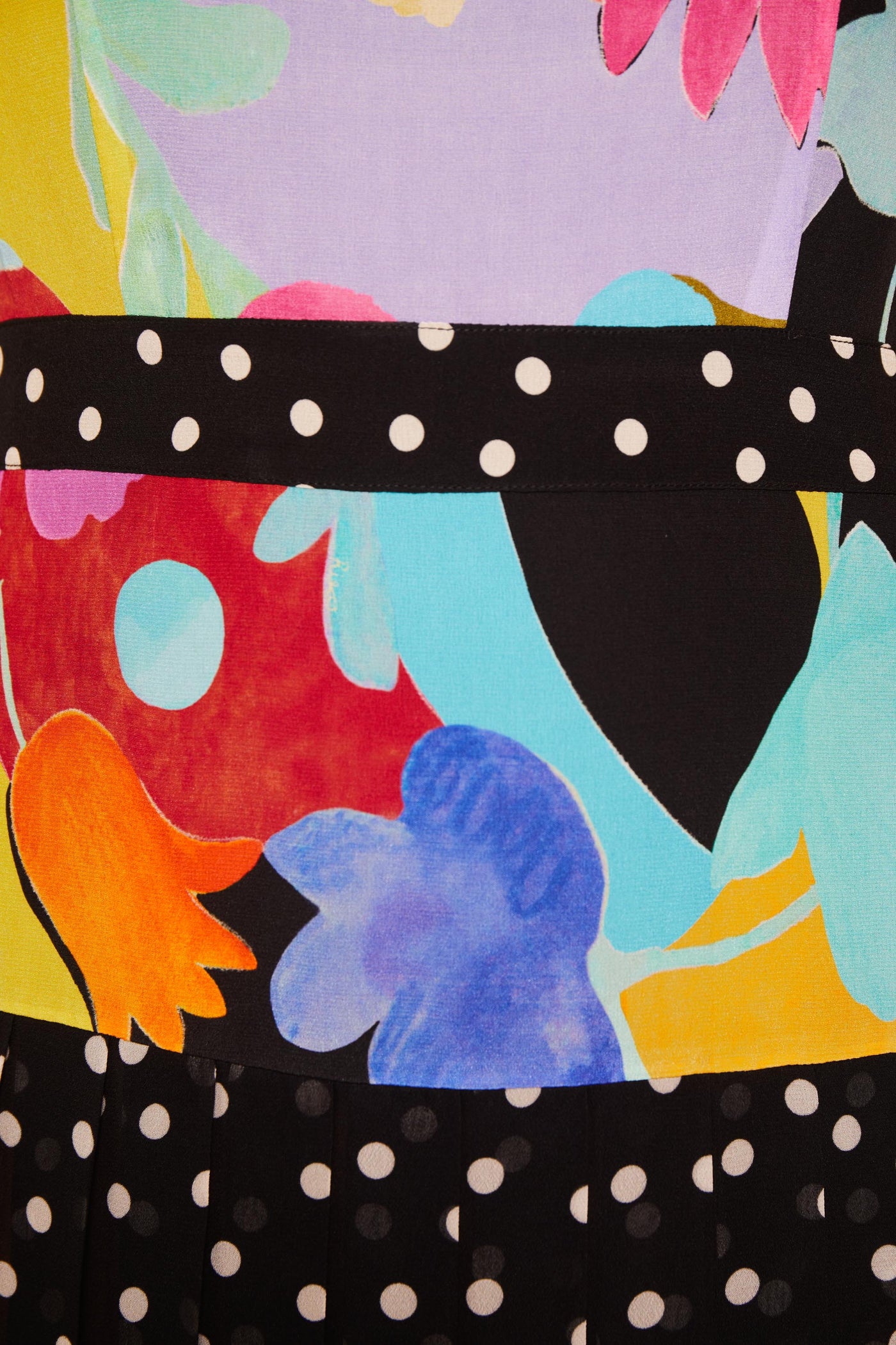 Close-up of Cozi - Tulip Spot Mix Multi silk crepe de chine, featuring a vibrant abstract floral print in red, blue, orange, and yellow with two black bands adorned in white polka dots—ideal for a waist-flattering dress.