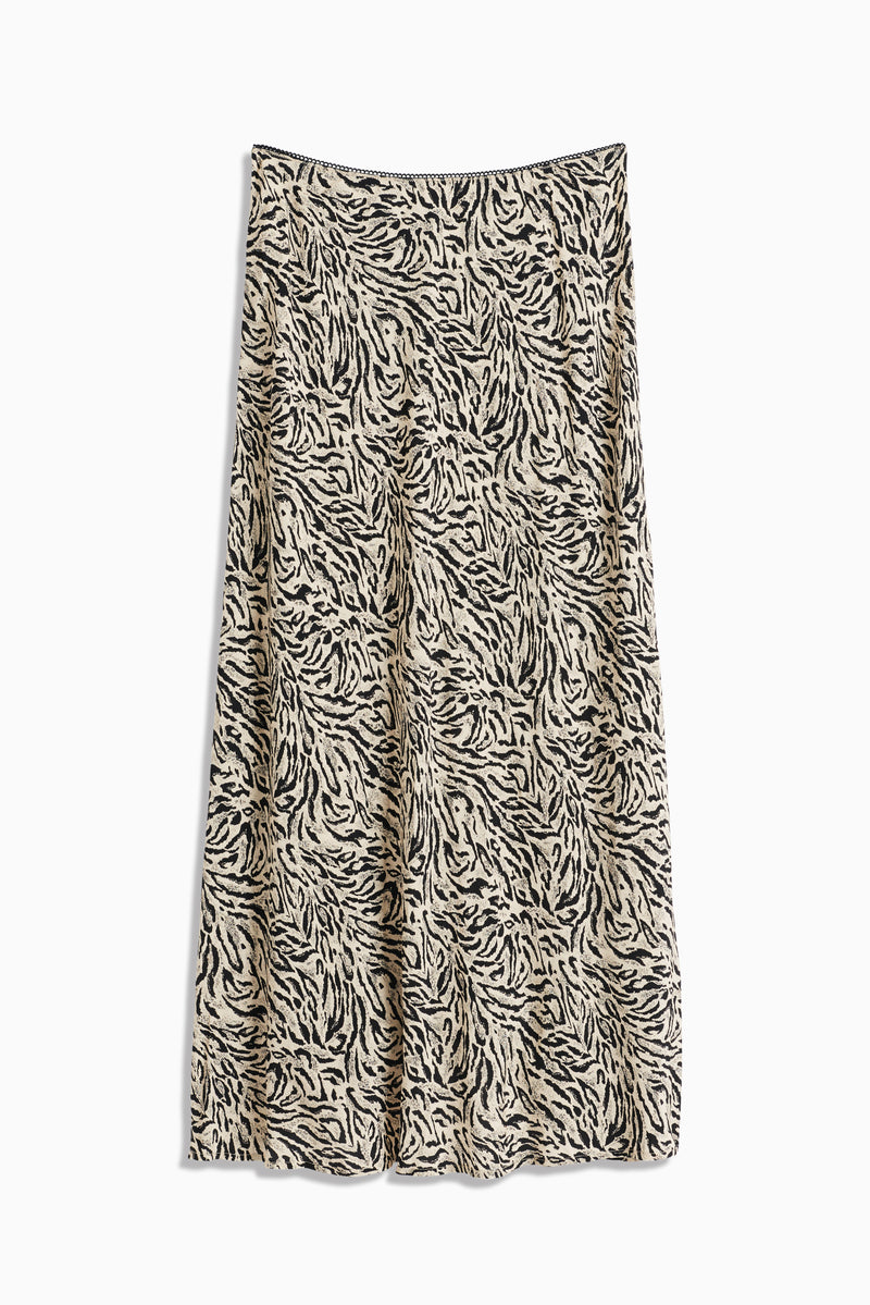 The Ardith - Sun Leo Tan is a beige A-line midi skirt with a black and white abstract tiger stripe print and an elasticated waistband, shown flat against a white background.