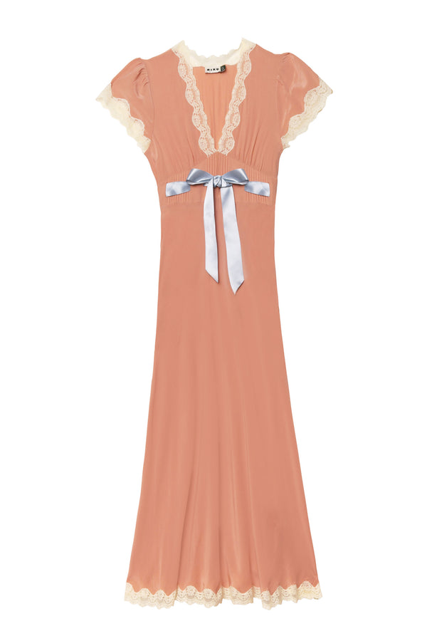 The "Marlice - Peach" dress features a vintage-inspired design with peach fabric, short lace-trimmed sleeves, a cream lace-edged V-neckline, fitted waist with a light blue satin bow, and a long skirt finished with lace at the hem.