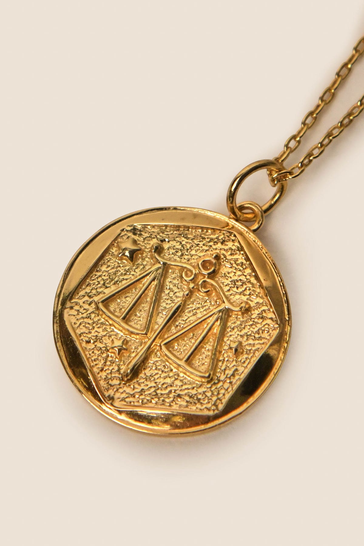 Zodiac - Libra necklace featuring a gold vermeil round pendant with raised zodiac scales and small star accents, suspended from a delicate chain on a neutral background—an elegant piece to enhance any Zodiac jewelry collection.
