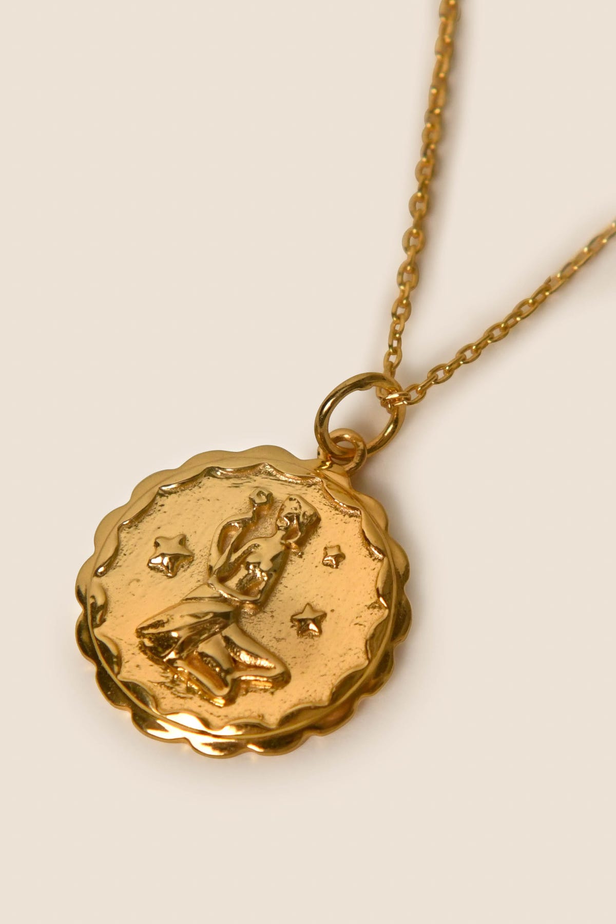 Zodiac - Virgo: A gold vermeil pendant necklace showcasing an embossed seated figure encircled by four stars and framed with a scalloped edge, suspended from a fine chain—a striking Zodiac-inspired Virgo necklace.