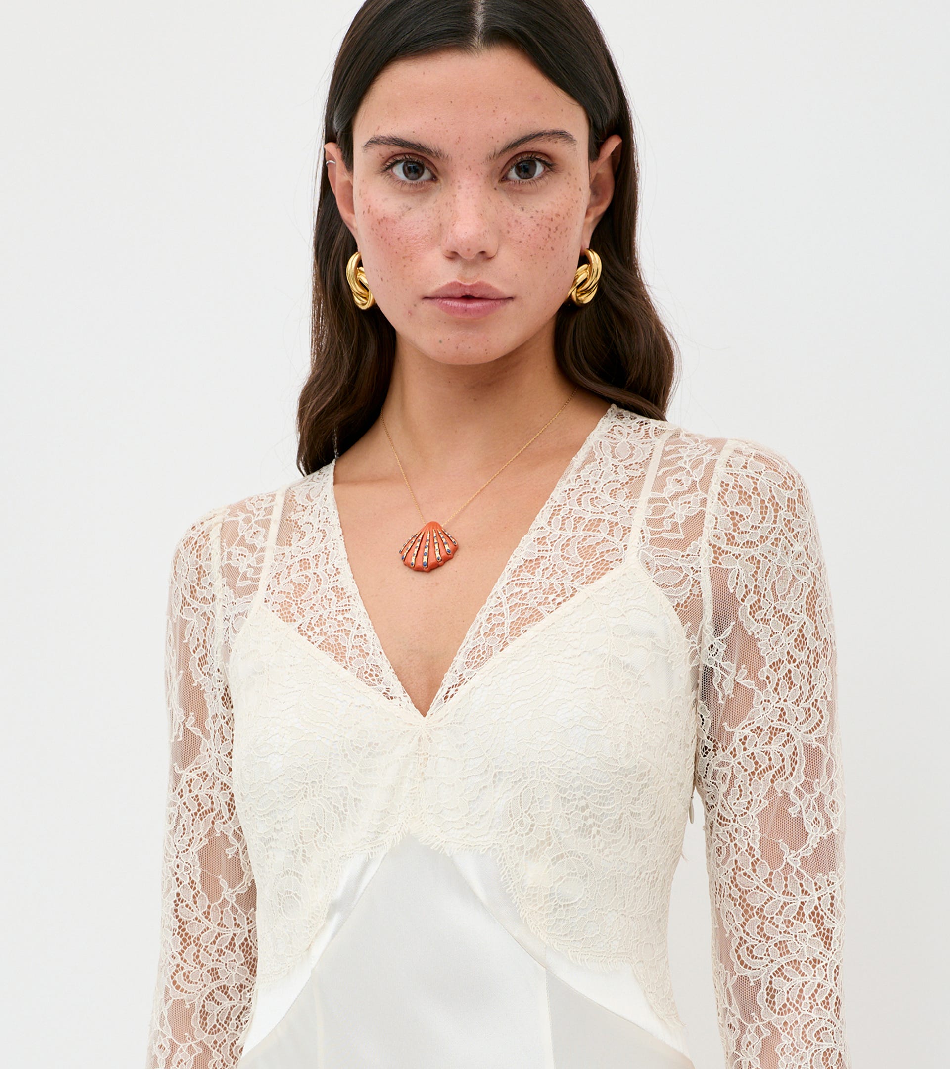 Woman wearing a white lace top with a plain background