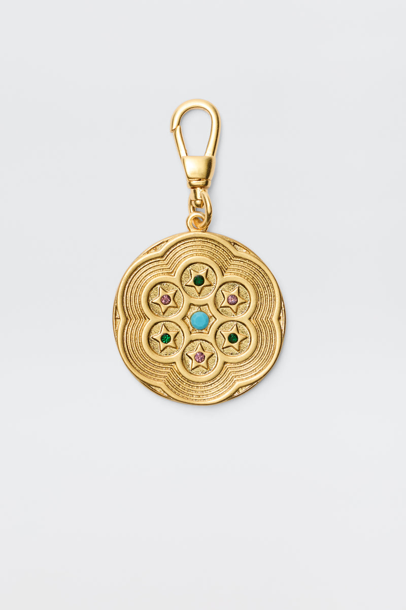 Chelle - Gold is a vintage-finished, gold-plated round charm pendant with engraved patterns and five star motifs set with colorful green, turquoise, or pink gems, secured by a swivel clasp.