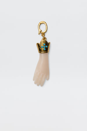 The Adara - Gold is a vintage-inspired gold-plated hand charm with a decorative crown set with turquoise stones, attached to a gold hook for a unique and elegant accessory.