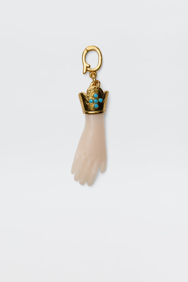 The Adara - Gold is a vintage-inspired gold-plated hand charm with a decorative crown set with turquoise stones, attached to a gold hook for a unique and elegant accessory.