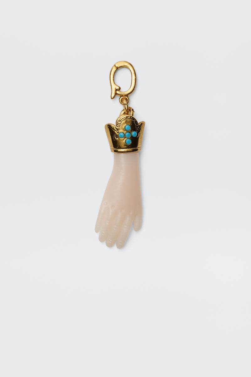 The Adara - Gold is a vintage-inspired gold-plated hand charm with a decorative crown set with turquoise stones, attached to a gold hook for a unique and elegant accessory.