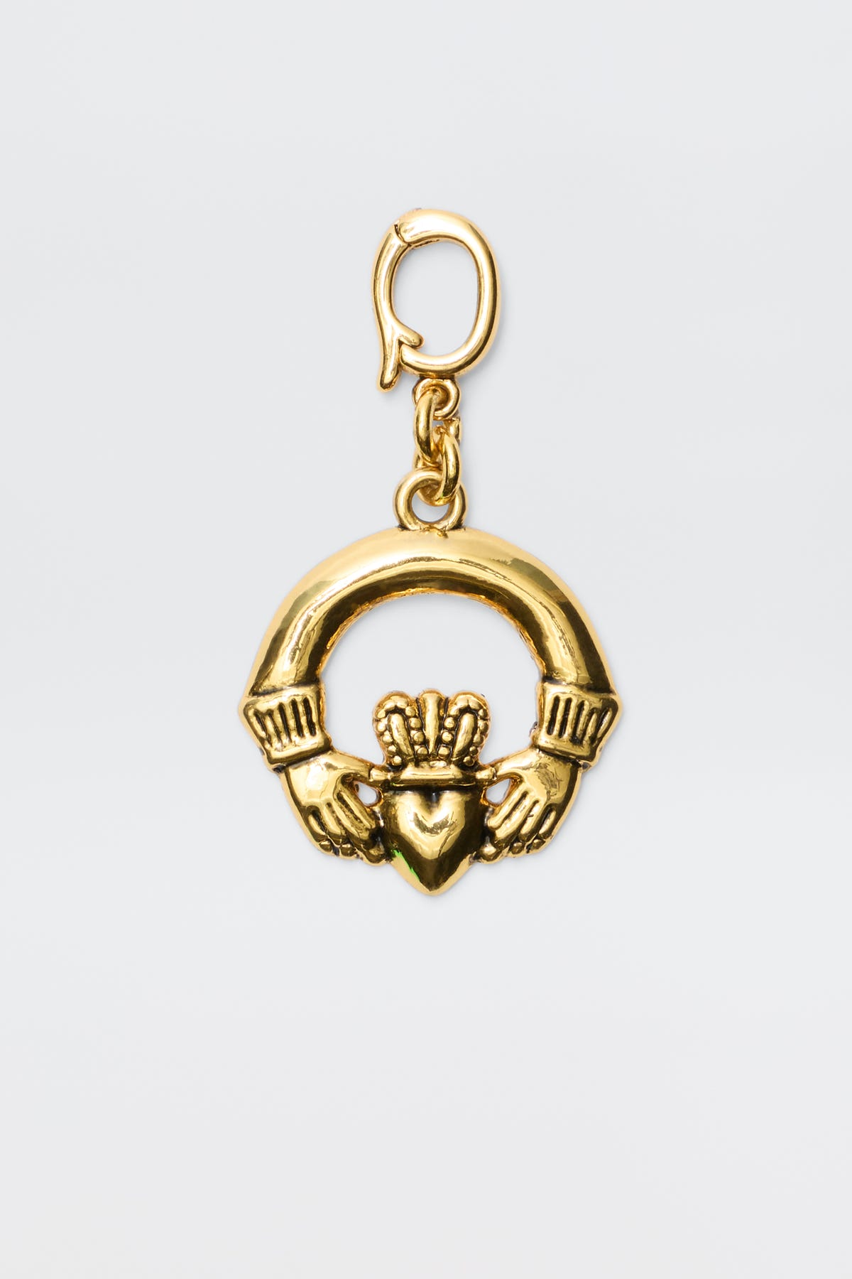 The Orsina - Gold is a gold-plated Irish Claddagh charm showing two hands holding a crowned heart, symbolizing love, loyalty, and friendship. It features a small clasp at the top for effortless chain attachment.