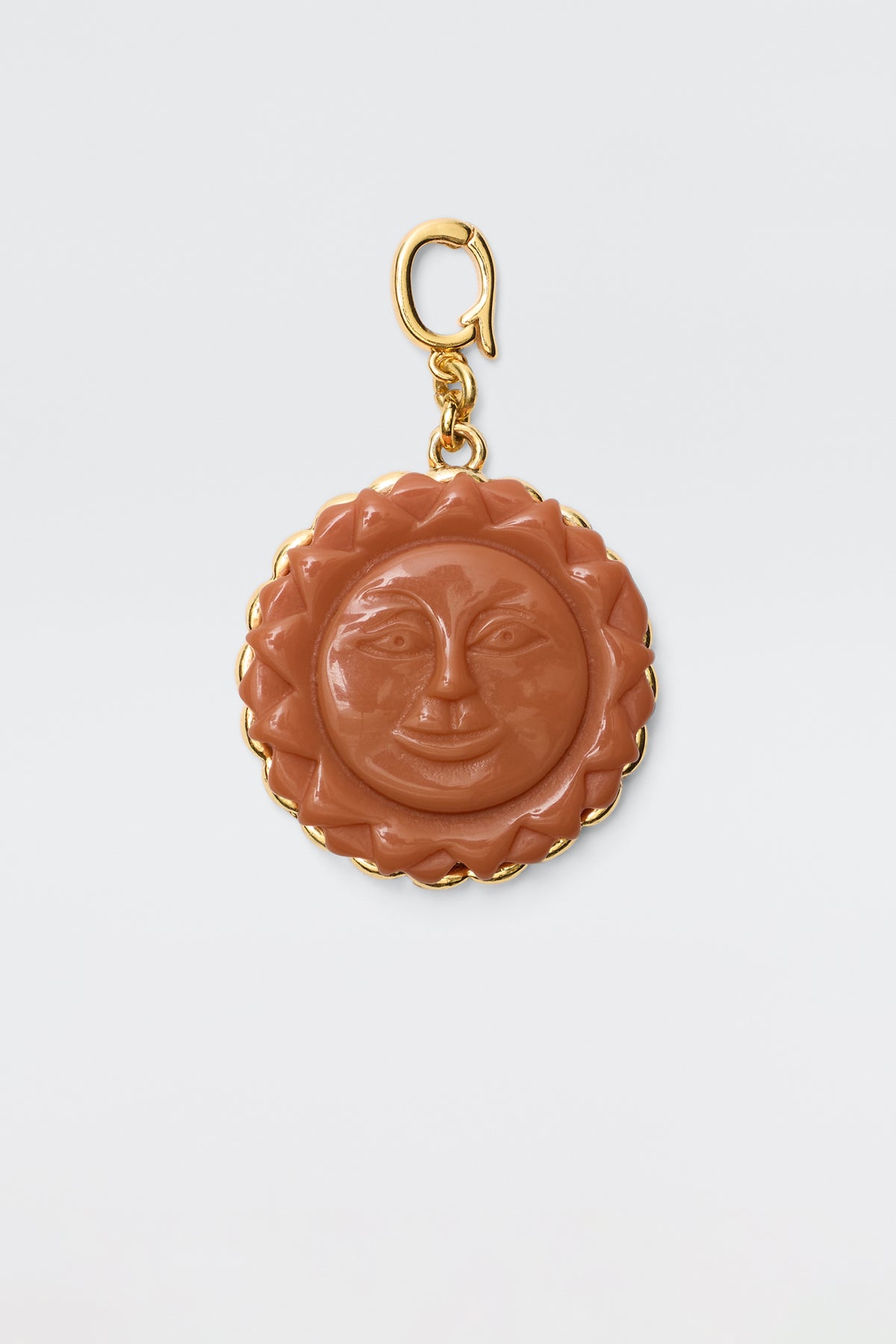 The Lillias - Orange is a round vintage charm pendant featuring a carved orange sun with a smiling face, surrounded by a gold scalloped border and attached to a gold clasp, displayed on a plain white background.