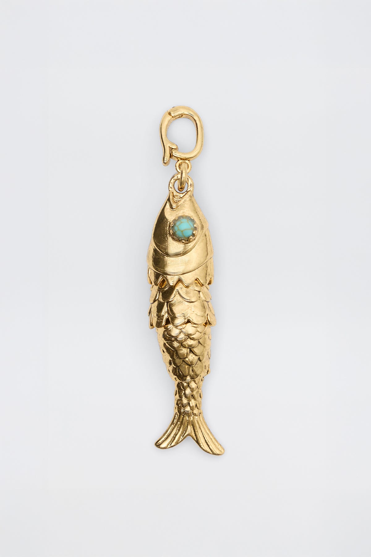 Nerissa - Gold: Fish-shaped pendant featuring detailed scales, a turquoise-colored eye stone, and a small top clasp for attaching to a chain, displayed on a plain white background.